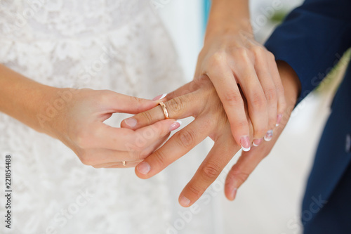 The bride carefully puts the ring on the finger of the future husband