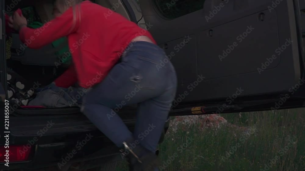 Blond girl is searching clothes in the car Blond girl is searching clothes in the car