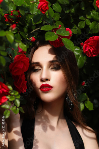 Portrait of  beautiful young woman in the rose garden  spring time  rose flowers blossoms.