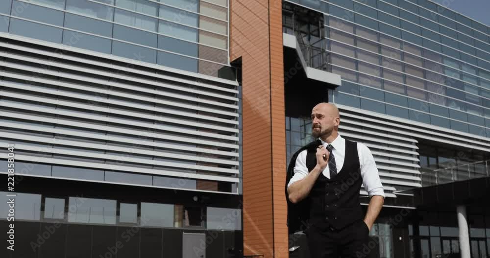 Happy attractive caucasian businessman walking outside near big office building and looking around. Happy attractive caucasian businessman walking outside near big office building and looking around.