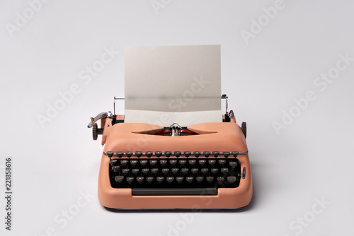 Retro typewriter coral color in studio. Studio shot.