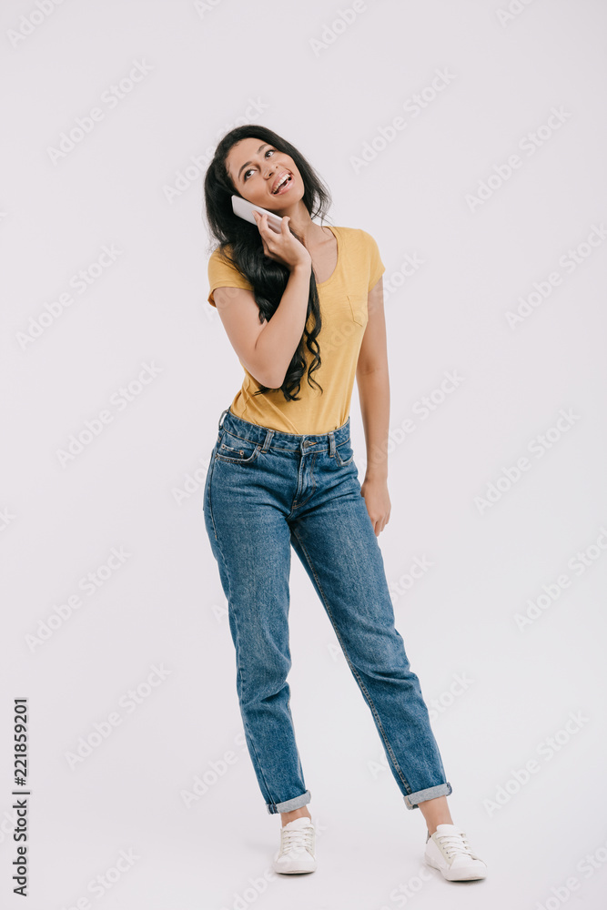 happy attractive african american girl talking by smartphone and looking up isolated on white happy attractive african american girl talking by smartphone and looking up isolated on white