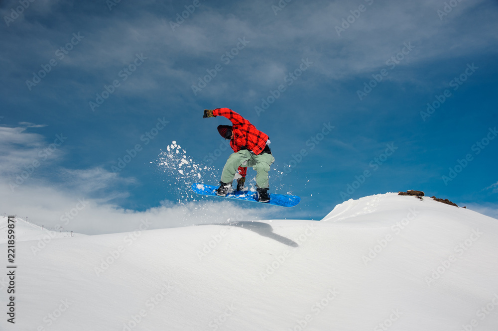 guy is jumping on a blue snowboard from a snowy mountain