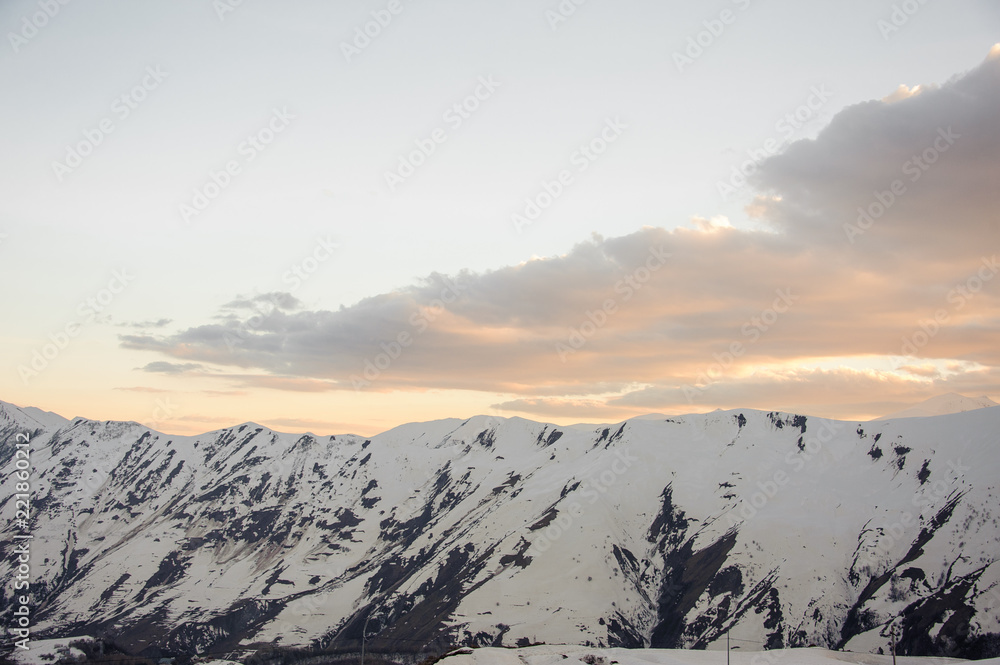 High mountains with snowy peaks against a beautiful pre-dawn sky with clouds