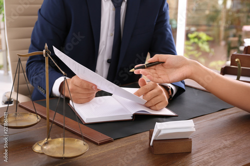 Lawyer working with client at table in office, focus on hands