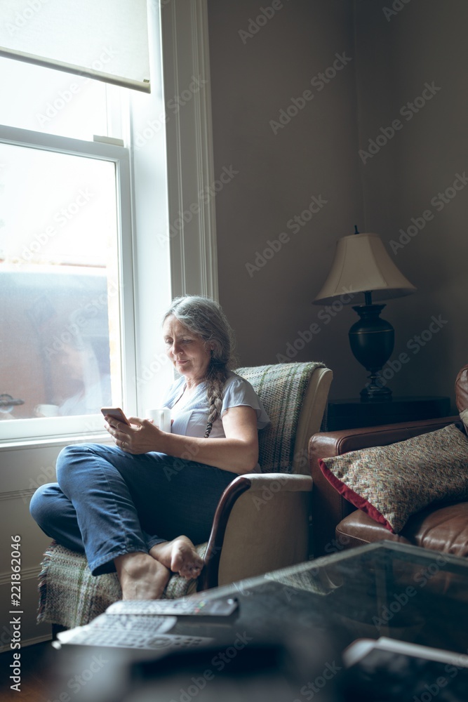 Senior woman using mobile phone in living room Senior woman using mobile phone in living room