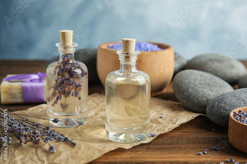 Fototapeta Naklejka Na Ścianę i Meble -  Bottles with natural herbal oil and lavender flowers on table against blurred background