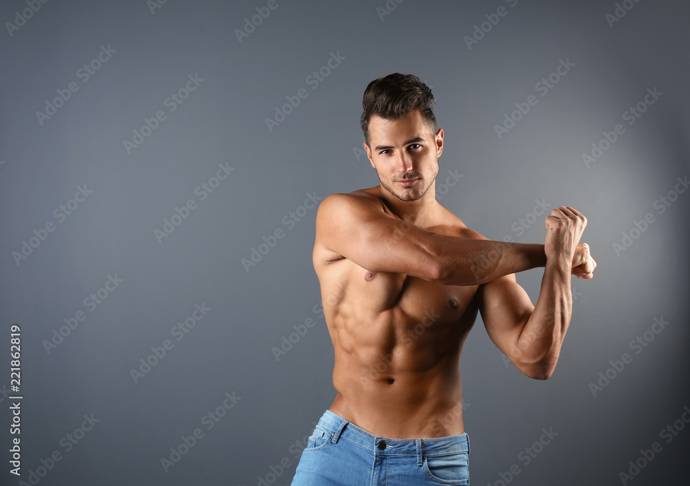 Shirtless young man in stylish jeans on grey background