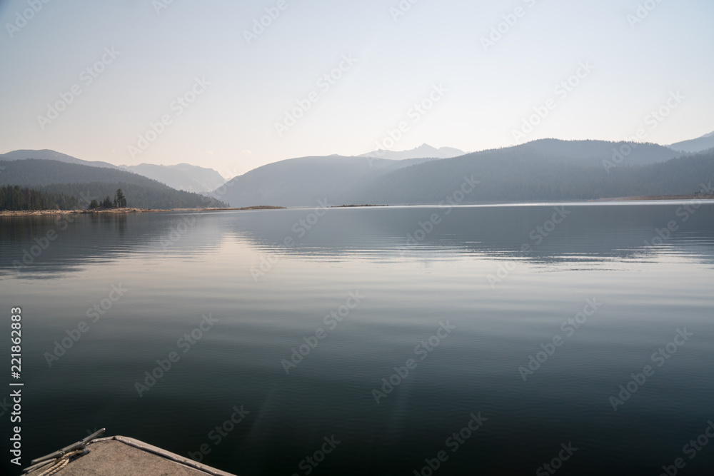 Pontoon boat heads out on a lake in the sierra nevada during a forest fire