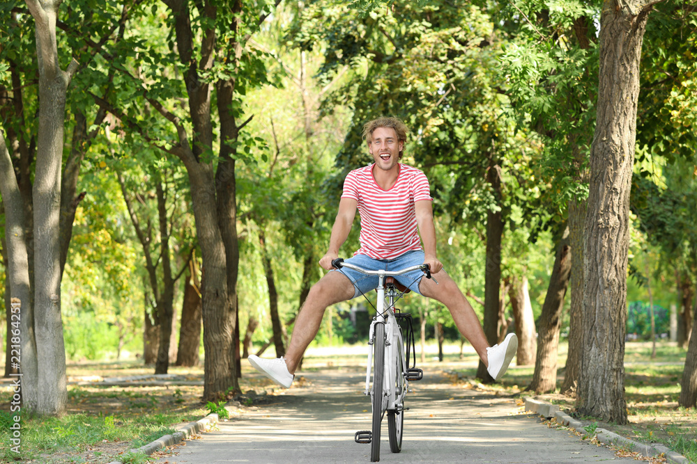 Obraz premium Handsome man riding bicycle in park on sunny day