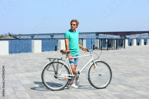 Handsome young man with bicycle outdoors on sunny day