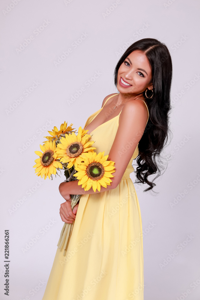 Young woman in tanned skin tone wearing summer fashion dress and holding a bunch of sunflowers in white isolated background. Young woman in tanned skin tone wearing summer fashion dress and holding a bunch of sunflowers in white isolated background.