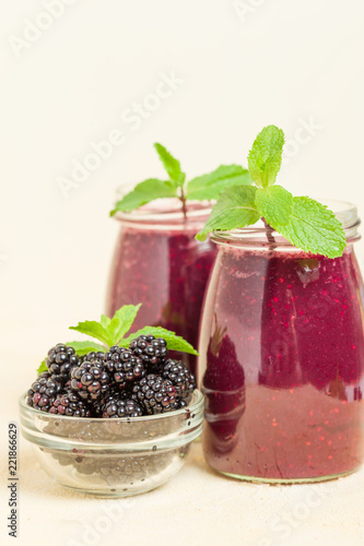 Blackberry smoothie - organic raw drink with fresh ripe forest berries on pastel yellow background.