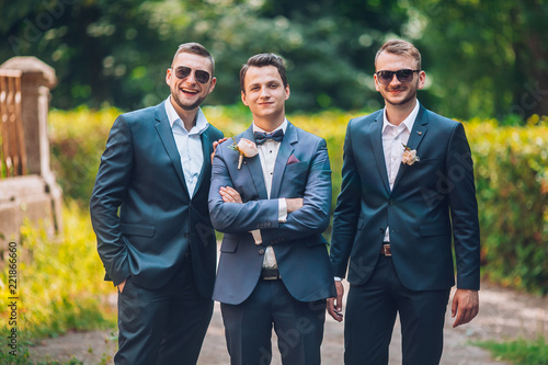 Obraz na płótnie Groomsmen and groom posing outdoors on the wedding day. Funny wedding moment for best groom friends. Mens hug each other. w salonie