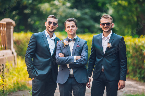 Groomsmen and groom posing outdoors on the wedding day. Funny wedding moment for best groom friends. Mens hug each other.