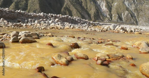 Yellow River, Chilecito. Van crossing river. Ocre Flowing water along rocky valley. Mountains and woods at background. Camera stays still. La Rioja, Argentina.