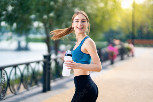 Fototapeta Naklejka Na Ścianę i Meble -  Happy woman with bottle of water, during morning jogging