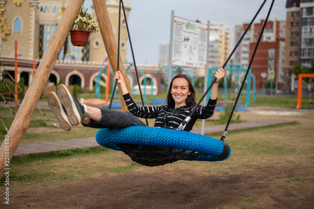 Brunette girl swinging on a hanging swing in the Park smiling with pleasure,  concept of freedom, day off, remember childhood Stock Photo | Adobe Stock