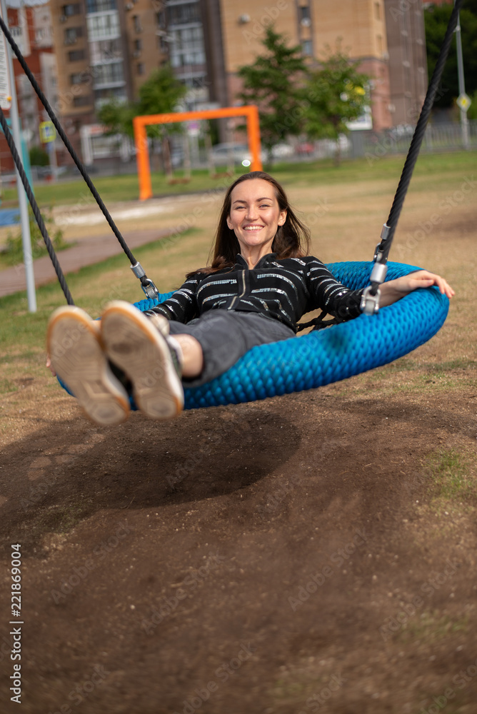 Smiling girl lying swinging on hanging swing, freedom concept, day off, remember childhood.