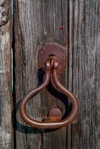 Aldaba de hierro oxidada en puerta antigua de madera.Congostro, Rairíz de Veiga. Ourense, Galicia. España.