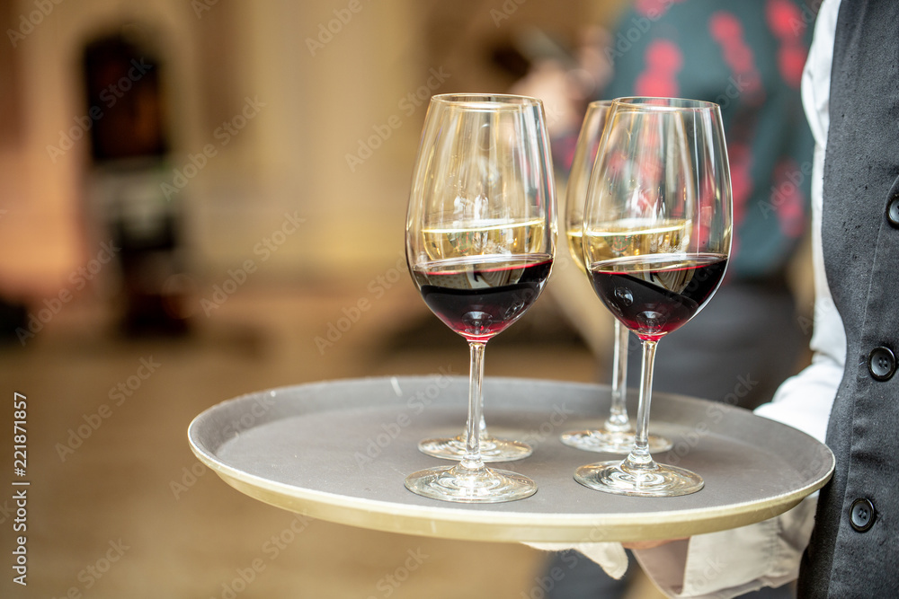 Glasses with wine on a tray. Meeting with guests. The waiter carries a tray with wine