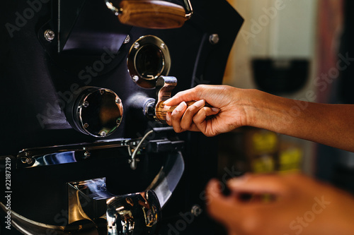 Close up of a woman hands pouring coffee beans into roaster photo