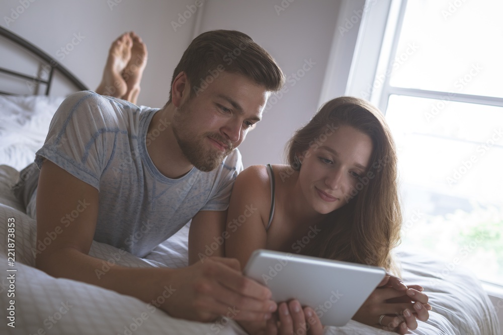 Couple using digital tablet in bedroom Couple using digital tablet in bedroom
