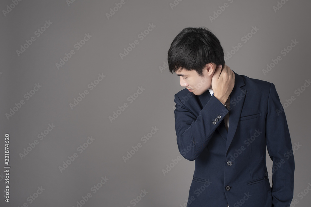 Business man is having neck pain ,grey background in studio Business man is having neck pain ,grey background in studio