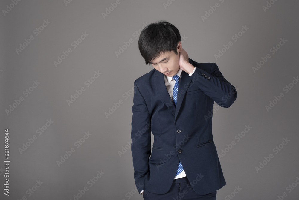 Business man is having neck pain ,grey background in studio Business man is having neck pain ,grey background in studio