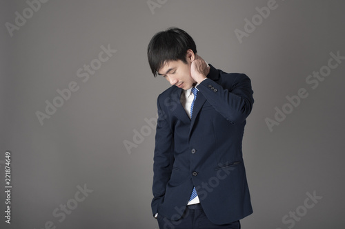 Business man is having neck pain ,grey background in studio