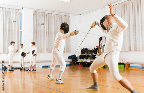 fencing  duel  of two l athletes in gym Fototapeta
