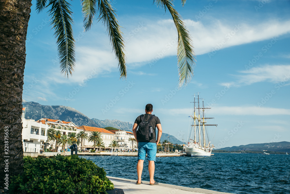 man standing at seaside with beautiful view of bay with big ship