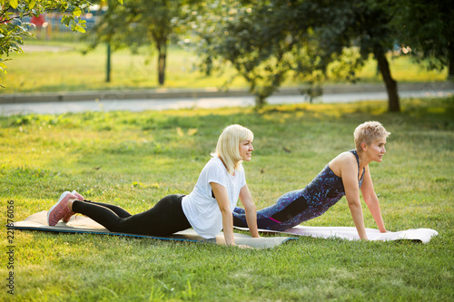 two adult women, go in for sports and gymnastics in the summer on the street in the park