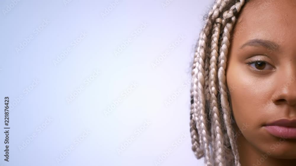 Half face of young African girl with dreadlocks looking at camera, serious face, white background. Half face of young African girl with dreadlocks looking at camera, serious face, white background.