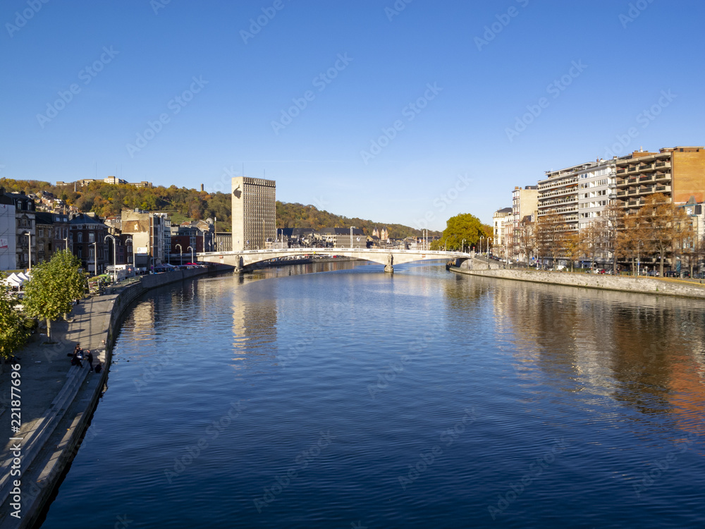View to Meuse River and Pont des Arches bridge with water surface reflections in Liege, Belgium against a clear November sky