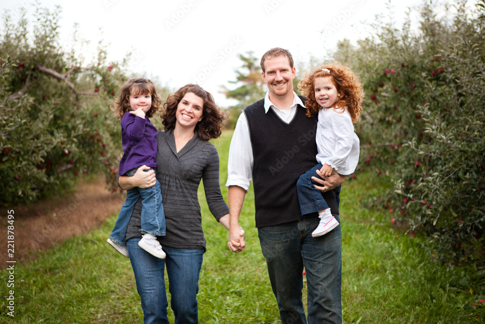 Happy Family Walking in Apple Orchard in Autumn Happy Family Walking in Apple Orchard in Autumn