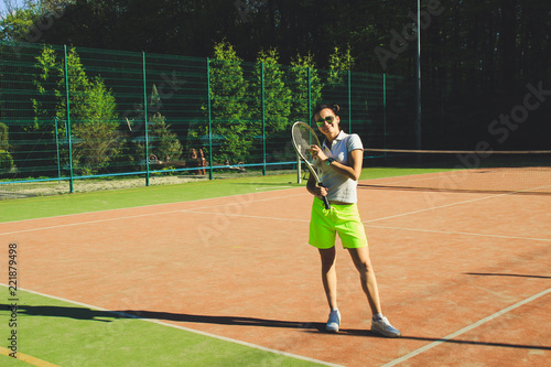 Portrait of girl with dart hair play tennis. Background tennis court.White t-shirt polo and yellow shorts.Sport shooting. © Yaroslav