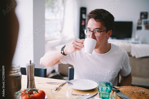 young asian man drinking coffee while having breakfast