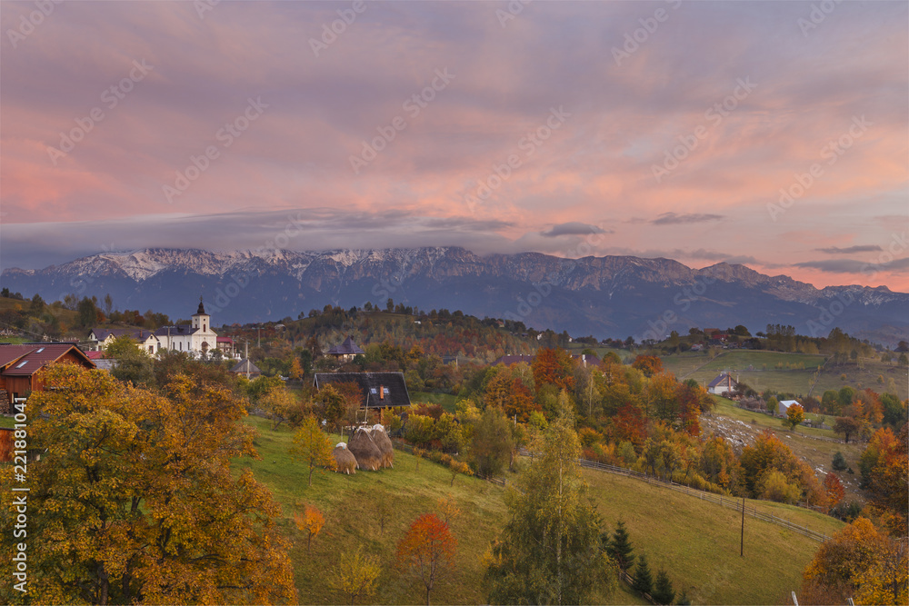 Autumn alpine landscape, alpine village with spectacular gardens and high snowy mountains in background near Bran, Magura, Transylvania, Romania.