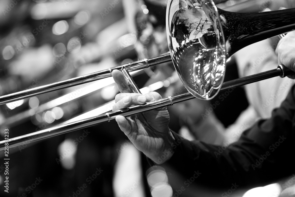 Fototapeta premium Trombone in the hands of a musician close-up in black and white tones 