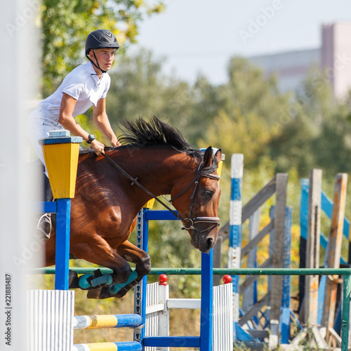 Young man riding horse on show jumping event. Sportsman on his course in equestrian competition