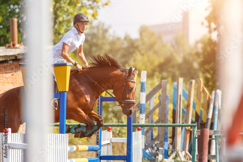 Young man riding horse on show jumping event. Sportsman on his course in equestrian competition