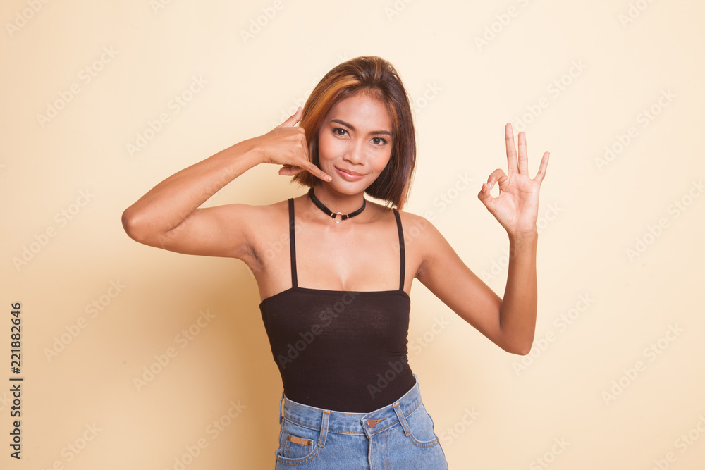 Young Asian woman show with phone gesture and OK sign. Young Asian woman show with phone gesture and OK sign.