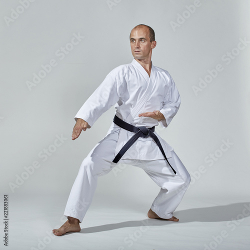 An adult athlete with a black belt trains a formal karate exercise