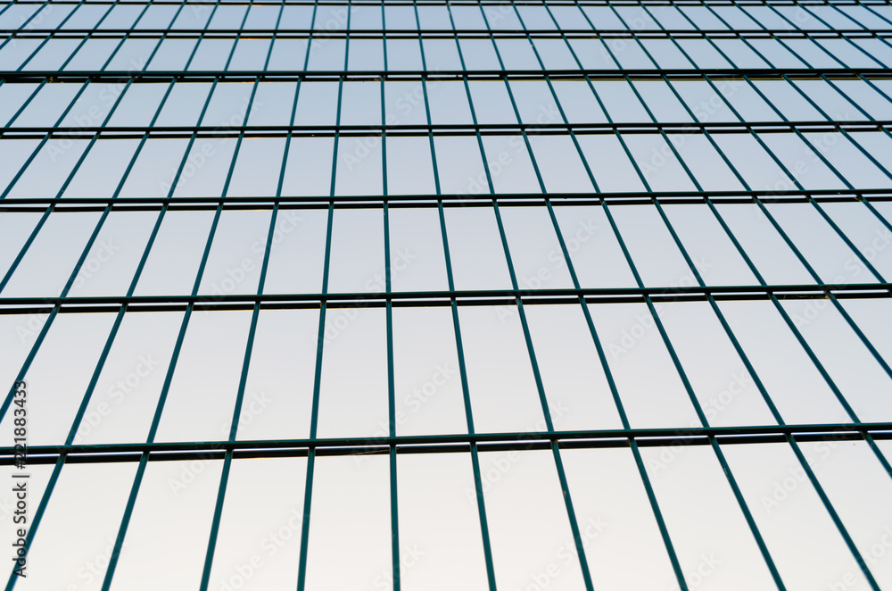 Metal mesh fence, fence on blue sky background.Rectangular abstraction. Metal mesh fence, fence on blue sky background.Rectangular abstraction.
