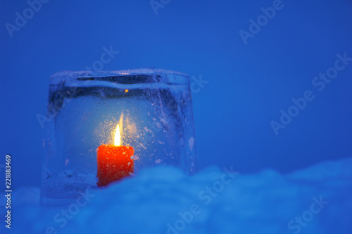 Ice lantern with red candle burning in winter evening twilight. photo