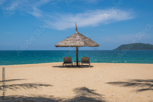 Sandy beach with two armchairs and an umbrella