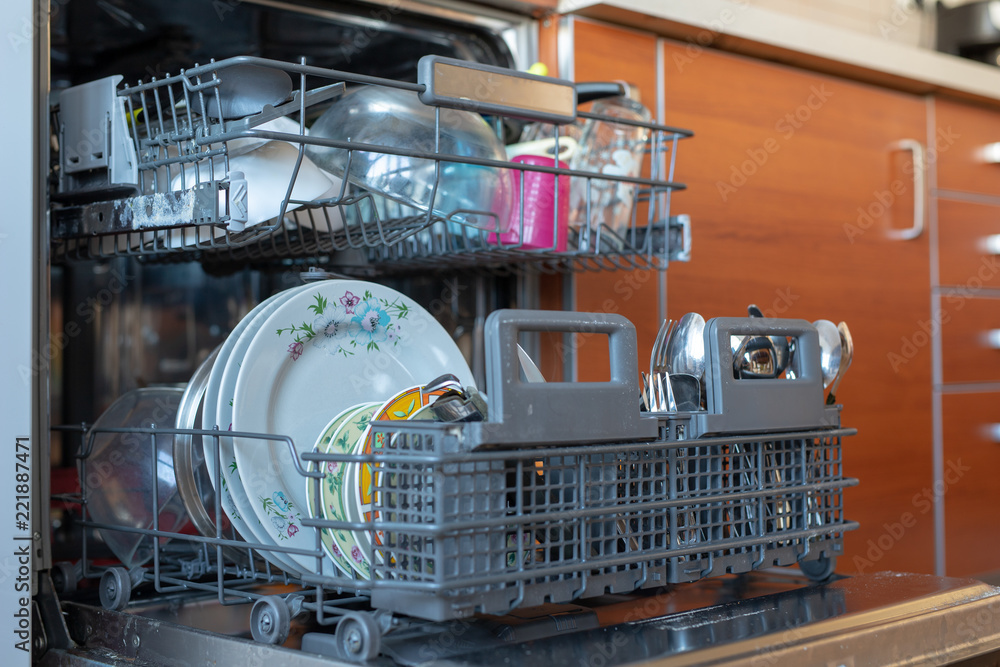 Dishwashing machine filled with dishes. Kitchen appliances helpful in home-made households.