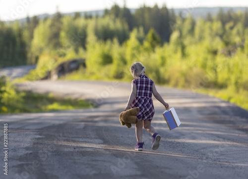 Tableau sur toile Caucasian girl child walking away with a bear and suitcase