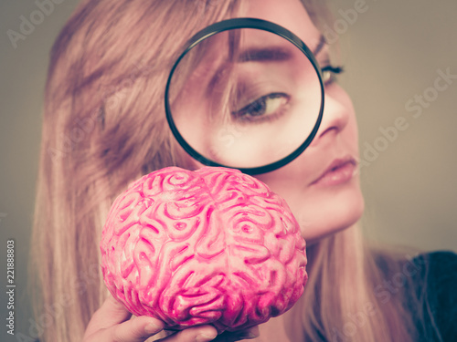 Quadro em tela Woman holding magnifying glass investigating brain